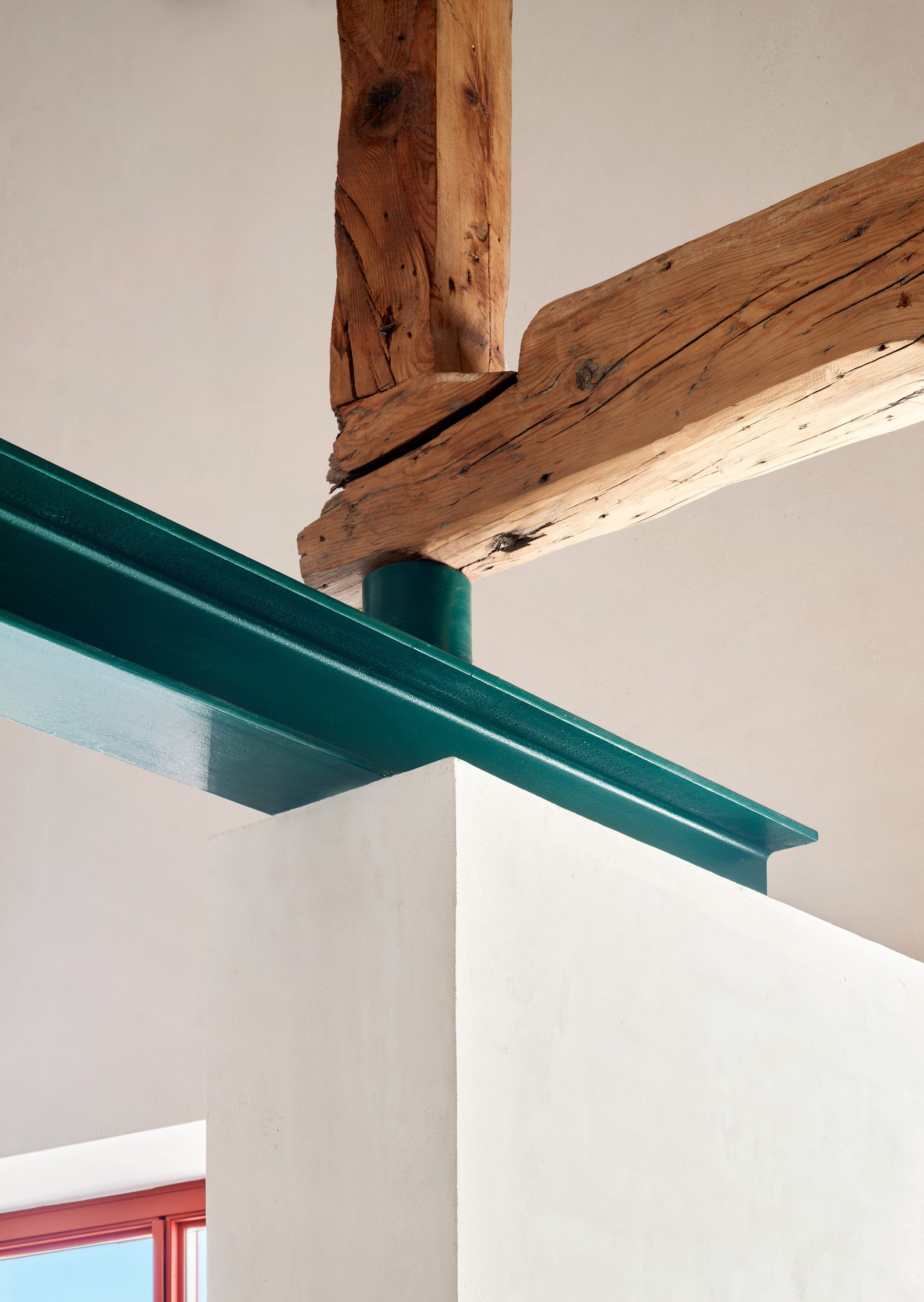 Encuentro entre viga de madera restaurada y perfil de acero verde