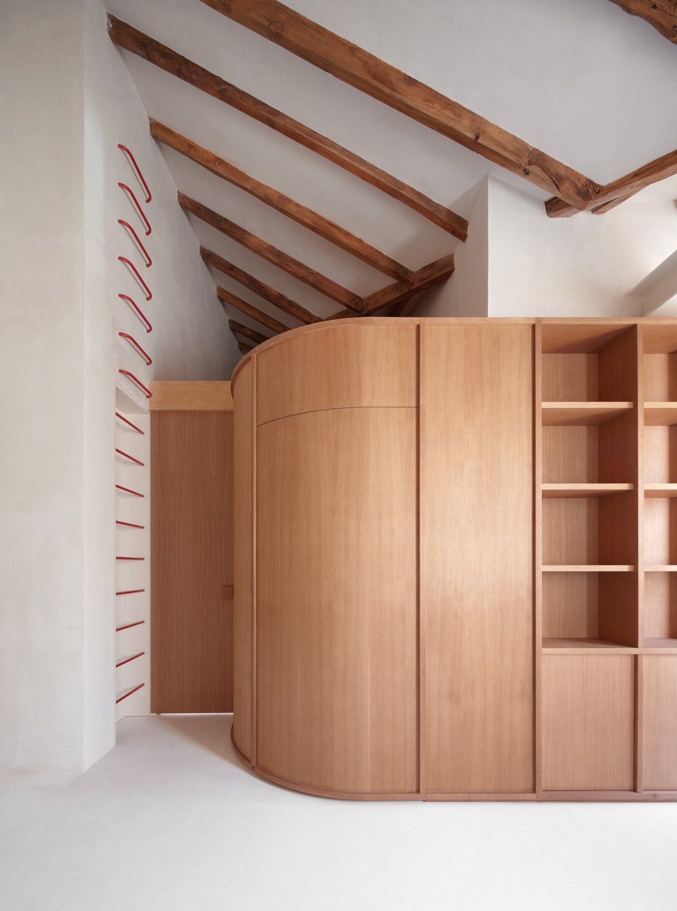 Orellana: armario curvo de madera, estantería y vigas de madera vistas