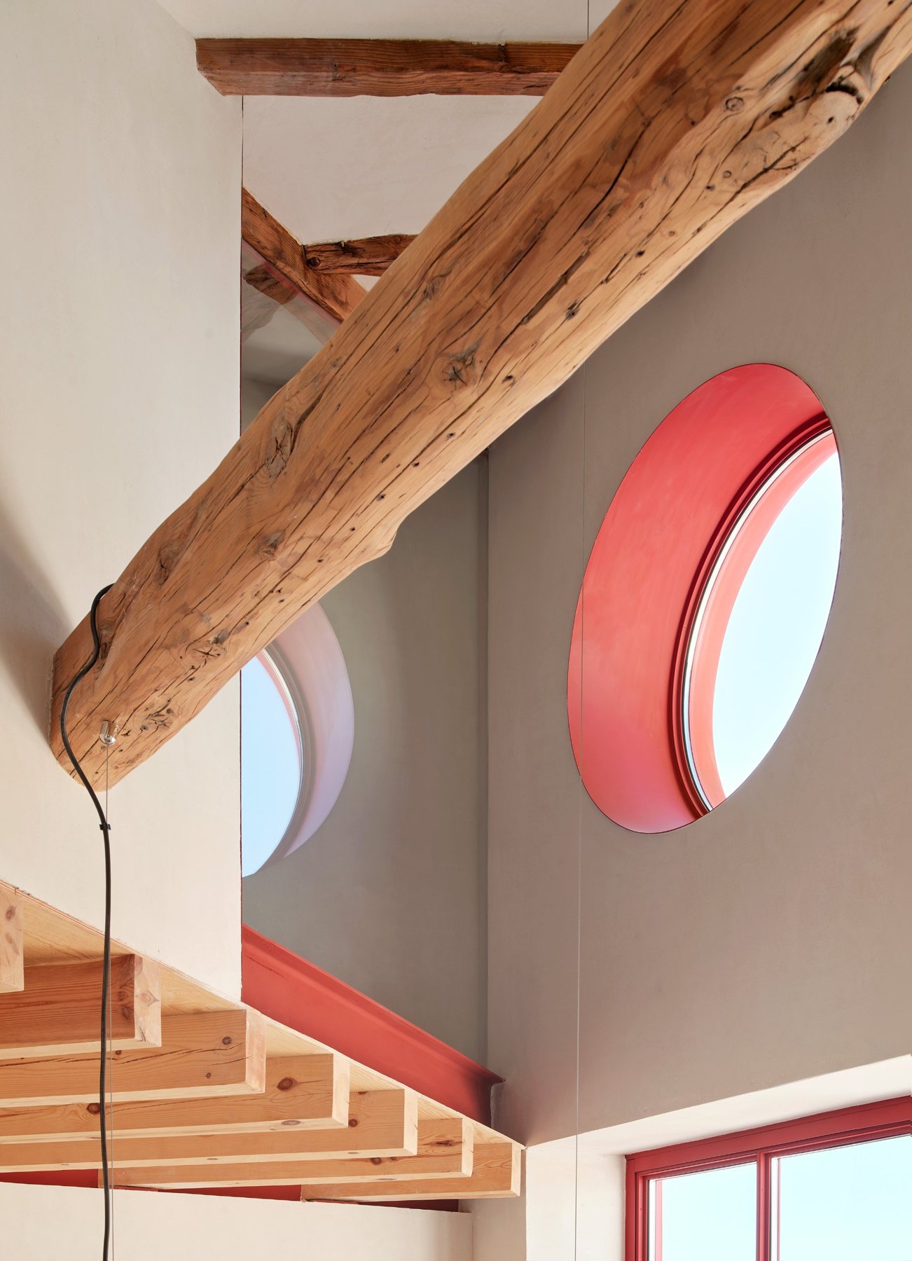Soma House: viga de madera restaurada, óculo con derrame rojo y forjado de madera